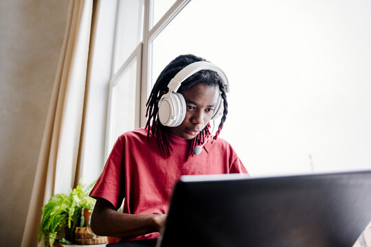 Young man wearing headset and using laptop at home