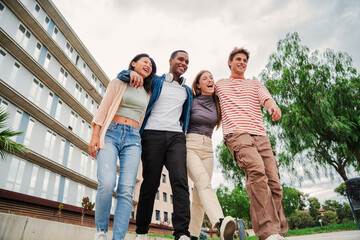 Group of young multiracial high school students walking and talking together. University classmates using a cellphone. Happy university friends carrying backpacks and having a conversation Slow motion
