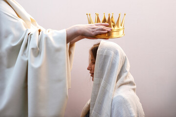 Hands placing a crown on a woman's head