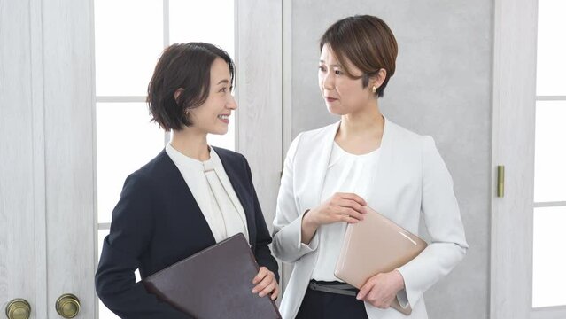 立ちながら話をするジャケットを着た女性2人