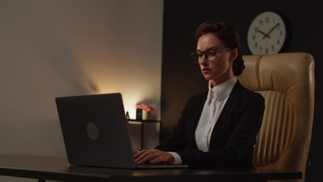 A young woman positive boss sitting on comfortable leather chair in office and using notebook. It specialist lady senior level programmer. Business analytic woman using computer. No paperwork, just
