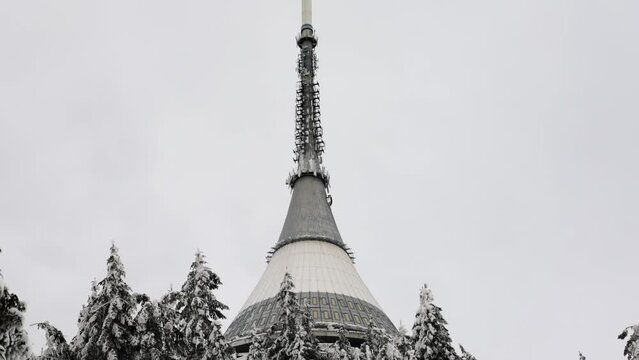 Reveal of tall television transmitter tower on mountain top in snowy winter