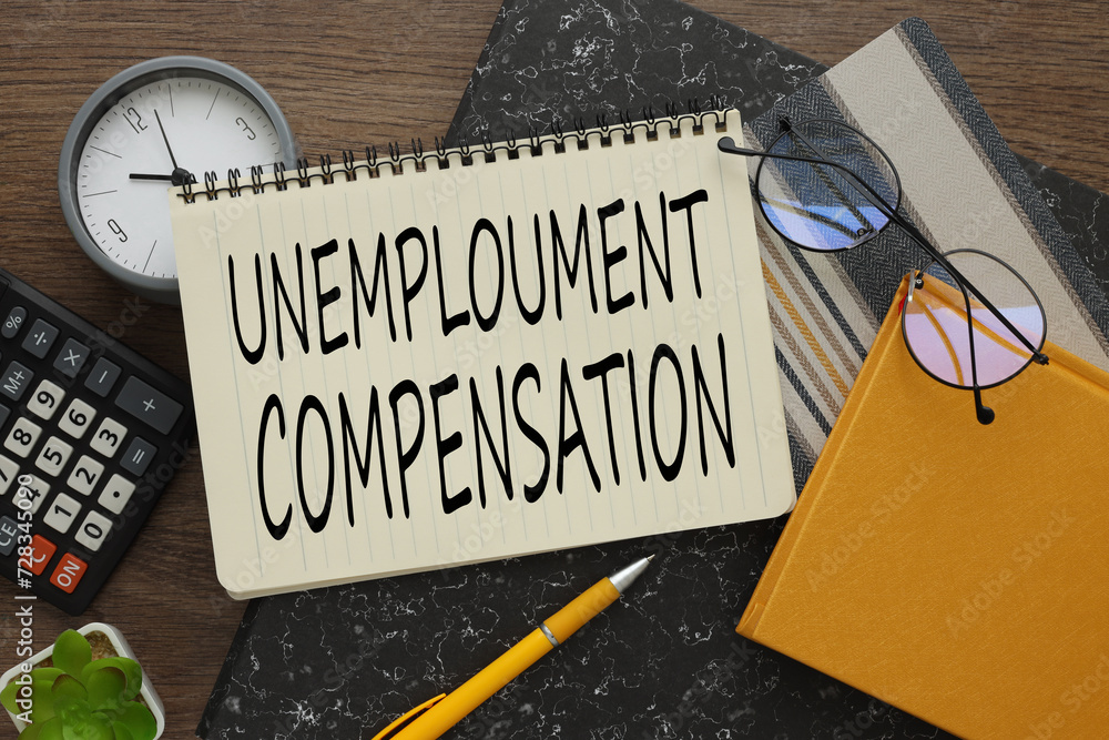 Poster unemployment compensation notepad on a gray folder. text on a notepad