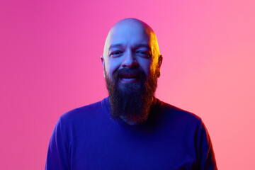 Gel portrait of bearded bald man in his 30s wearing blue sweater, smiling, looking in camera...