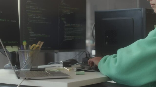 Cropped shot of female IT specialist typing programming code on computer with dual monitor while working at office desk