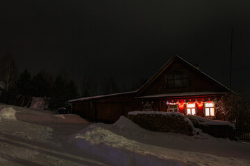 View from a hill on wooden houses covered snow at night. Scenery of ski resort with lights. Theme of travel.