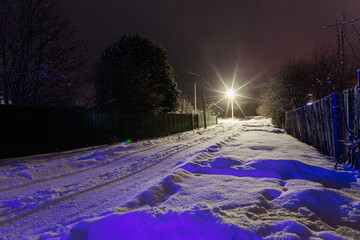 Road covered snow with lanterns in the north village. Rural view in winter.