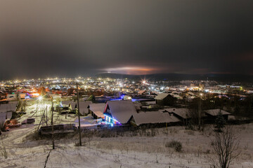 View from a hill on wooden houses covered snow. Scenery of ski resort with lights. Theme of travel.