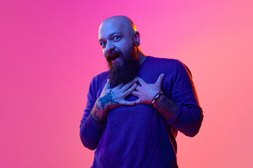 Portrait of bearded bald man in swear expressing emotions, standing with shocked face against pink...
