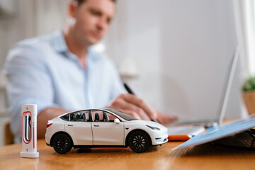 Focus scale EV car and charging station mockup model on blurred background of automotive design...