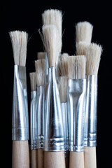 Paint brushes isolated on black background. Vertical image