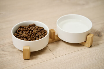 Obraz na płótnie Canvas Bowls of dog food and water on kitchen floor, Animal feeding and pet care, Place to feed a pet