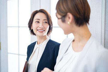 立ちながら話をするジャケットを着た女性2人