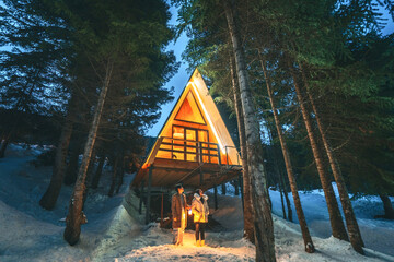 Couple standing in the snow in a forest shelter Romantic winter triangle house in Georgia.