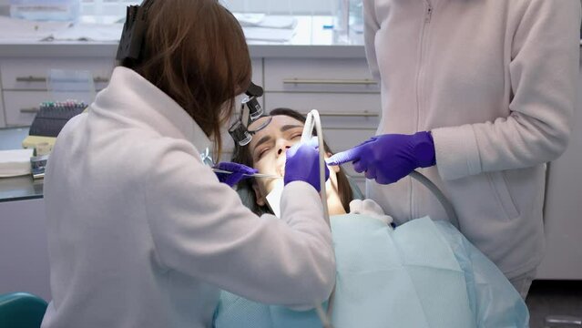 A young woman is undergoing treatment in a modern dental clinic. The concept of dental treatment, whitening, installation of veneers and braces, cleaning the oral cavity.
