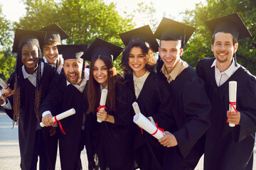 Portrait of diverse smiling laughing happy multiracial international graduates students standing in...