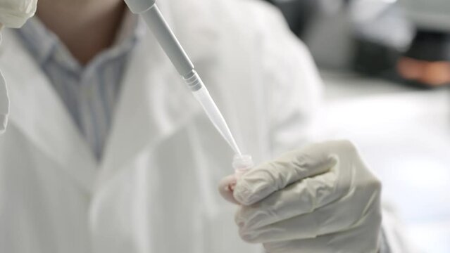 Closeup shot of scientist hands in white gloves getting sample using absorption pipette