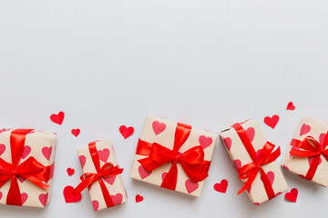 Top view photo of valentine day decorations gift box with red ribbon bow on colored background....
