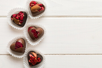 chocolate sweets in the form of a heart with fruits and nuts on a colored background. top view with space for text, holiday concept