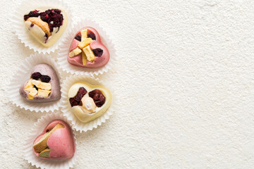 chocolate sweets in the form of a heart with fruits and nuts on a colored background. top view with space for text, holiday concept
