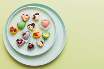 Plate with different chocolate on colored background. Assortment of fine chocolates top view vith copy space Health and obesity concept