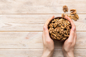 Woman hands holding a wooden bowl with walnut nuts. Healthy food and snack. Vegetarian snacks of different nuts