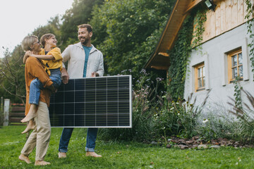 Father mother and daughter standing in garden with solar panel. Solar energy and sustainable...