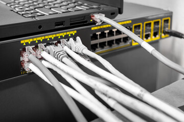 Network Gigabit Smart PoE Switch with laptop connected network cables getting configured on the...