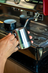 Fototapeta na wymiar Boilink milk in a coffee machine for preparing cappuccino in a coffee shop - stock photo