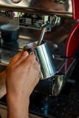 Boilink milk in a coffee machine  for preparing cappuccino in a coffee shop - stock photo