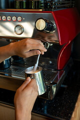 Boilink milk in a coffee machine  for preparing cappuccino in a coffee shop - stock photo