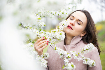 Obraz na płótnie Canvas Healthy happy woman on spring outdoors. Smiling young woman on the spring garden enjoy blooming flowers of tree. Enjoy Nature. No allergy.