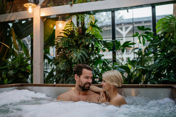 Beautiful mature couple relaxing in hot tub, enjoying romantic wellness weekend in spa. Concept of Valentine's Day.