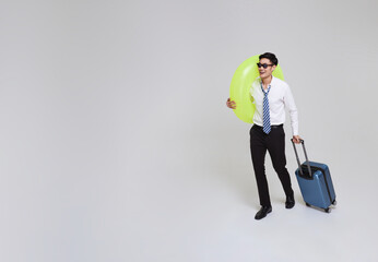 Business travel summer time. Asian businessman holding luggage and swim inflatable ring going to travel on summer holidays isolated on white copy space background.