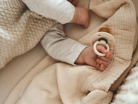 Baby with a nipple. Close up of baby hands with pacifier. Focus is on hands. Newborn sleeping on a blanket holding a pacifier in his hand