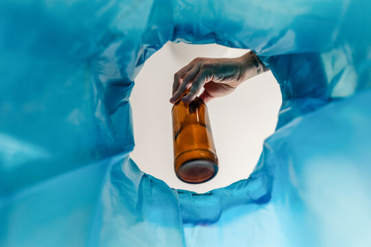 Man throwing glass bottle into recycling bin. Empty alcohol bottle, throwing, New Year's resolutions, drink less alcohol healthy lifestyle without alcoholic drinks.