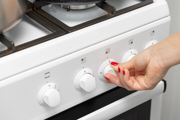 a woman's hand rotates the selector on a gas stove.