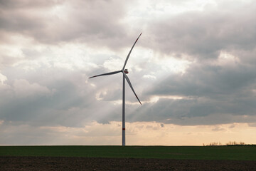 Fototapeta premium Wind turbine in the middle of a field at sunset