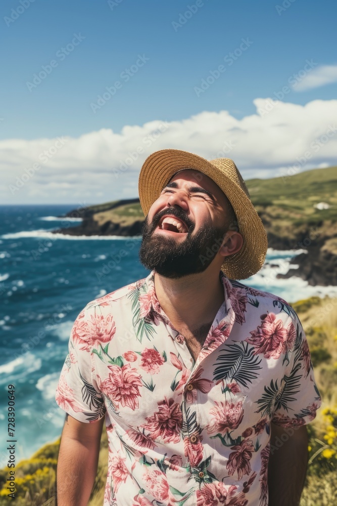 Poster a man wearing a hat stands on a cliff overlooking the ocean. this image can be used to represent adv
