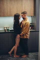 A young couple is standing in the kitchen. A girl in shorts with bare legs. The girl takes off the...