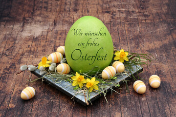 Frohe Ostern: Narzissen mit Ostereiern auf einer Schale dekoriert. Das Osterei ist mit Frohe Ostern...