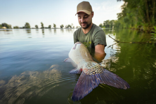 Fishing background. Young man hold big carp in his hands.	
