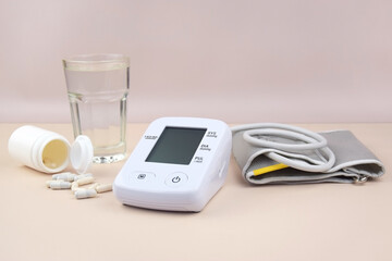 Digital blood pressure tonometer and pack of pills on a light background with copy space.