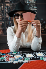 portrait of young caucasian woman with cards and chips playing poker at casino