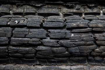 Charred wooden logs of a barn, bathhouse, house after a fire.
