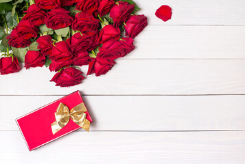 Mockup with red roses and gift box on white wooden background.