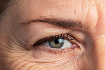 Fototapeta premium Close up of elderly woman's eye with wrinkles and hooded eyelid