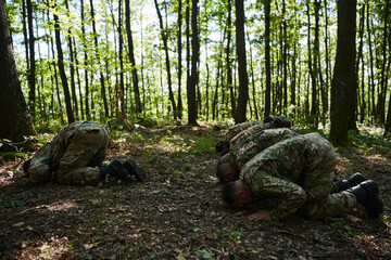 A dedicated group of soldiers engages in Islamic prayer amidst the challenging and perilous conditions of a military operation in dense forested areas