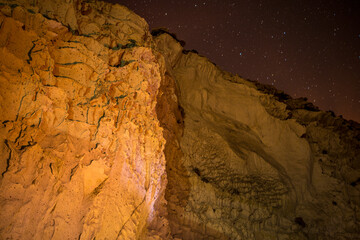 A celestial spectacle unfolds as stars adorn the night sky above calcareous mountain rocks, creating a cosmic panorama of majestic beauty.