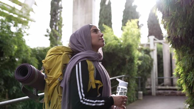 muslim woman in hijab with traveling backpack in nature